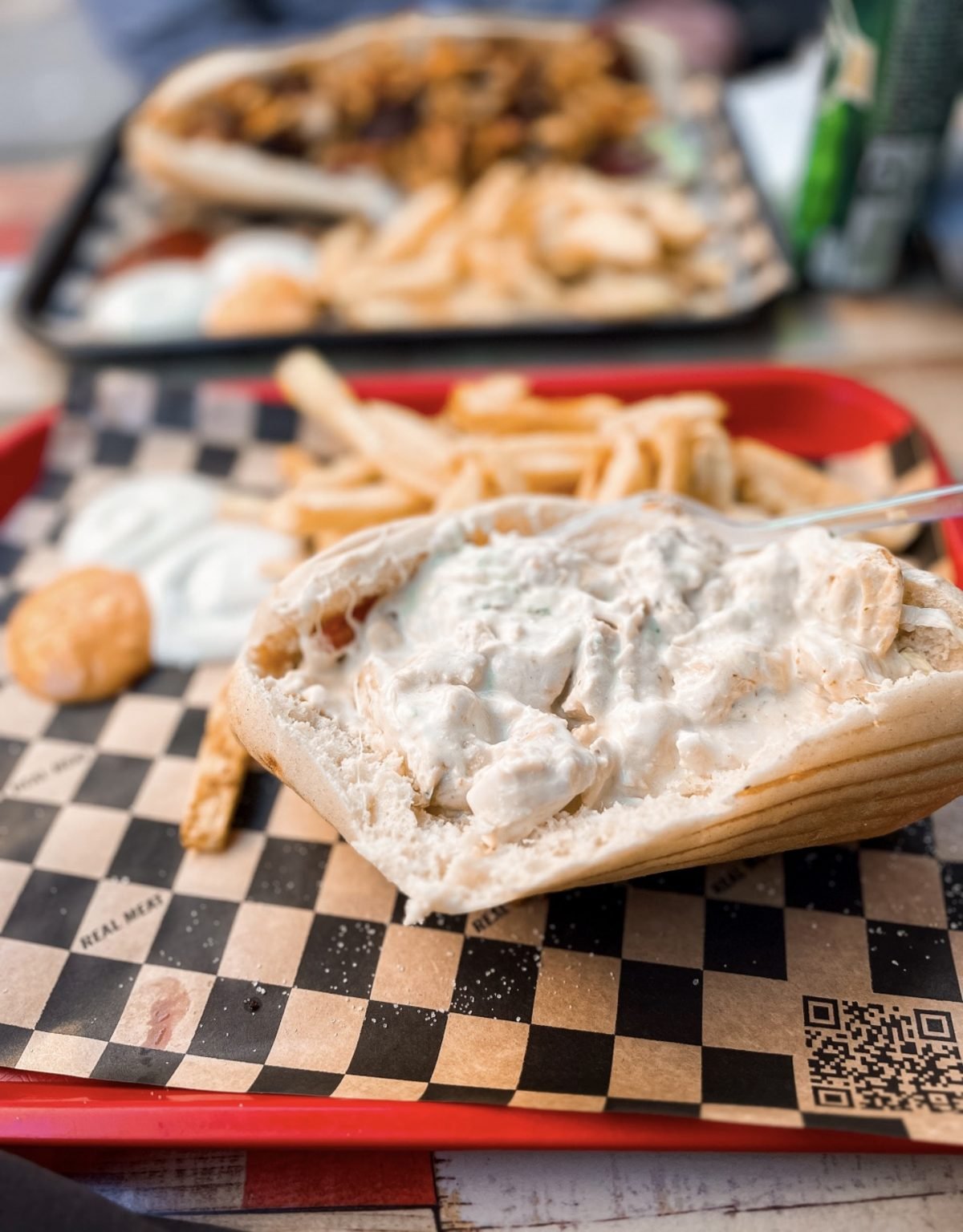 A loaded pita and fries on a checkered paper-lined tray