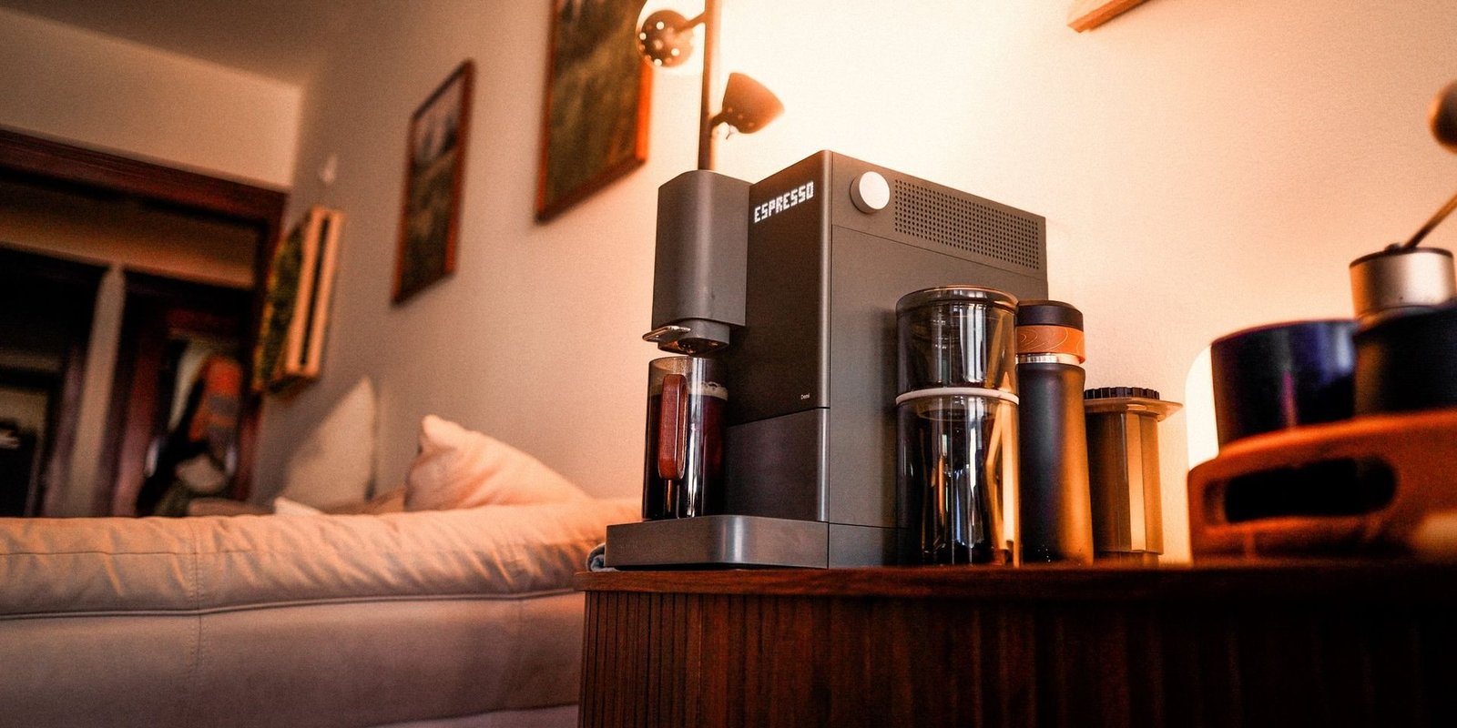 A Terra Kaffe Demi espresso machine and coffee gear on a walnut cabinet in warm lamplight