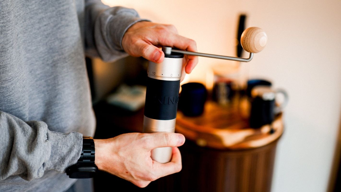 Two hands turning the K6’s wooden-knobbed crank