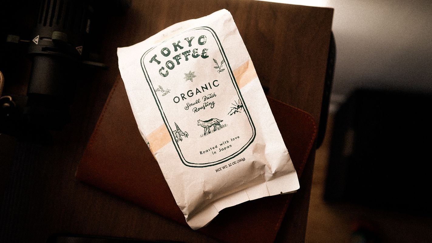 The Tokyo Coffee bag lying on a leather notebook on a dark desk