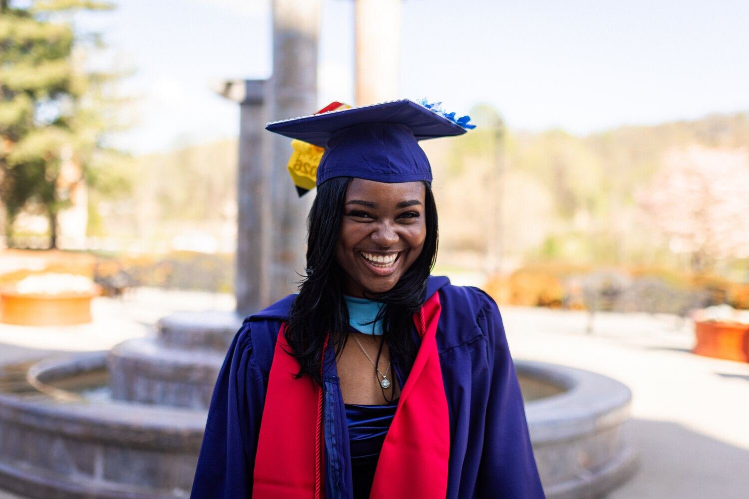 A graduate in cap and gown by a fountain